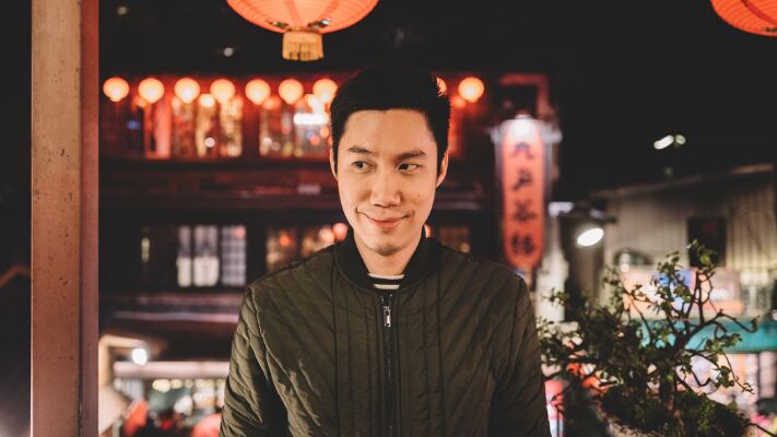 Brandon Oda standing beneath red lanterns at night in Asia